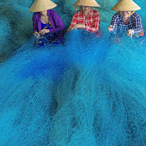 Vietnam. Women repairing fishing nets