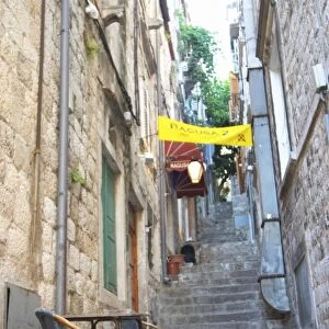 View from the Prijeko street up a narrow street with steep stairs. Two rattan chairs