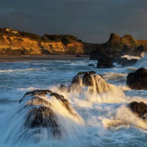 Waves crashing on rocks and washing down the sides at sunset