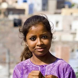 Young Indian girl aged 15 in purple in front of village of Jodhpur in Rajasthan India