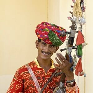 Young man in traditional costume playing old fashioned guitar instrument called a
