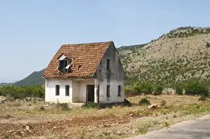 Albania Prints: An abandoned house falling to pieces on the dry plain along the road between Shkodra