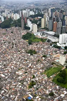 Sky Scraper Prints: Aerial view of crowded favela housing contrasts with modern apartment buildings in Sao Paulo