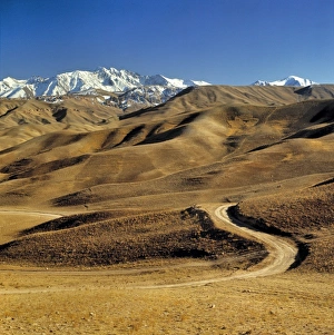 Foothill Prints: Afghanistan, Hindu Kush Mountains. A lonely dirt road leads into the barren foothills