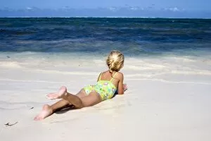 Africa, Kenya, Malindi. Young girl relaxes on the beach while watching the ocean