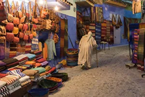 Alley Prints: Africa, Morocco. An elderly man walks past tourist shops along a street in the blue