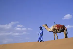 Images Dated 25th November 2012: Africa, Morocco, Tinfou (near Zagora) Man in traditional dress leading camel on sand dunes