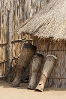Tribe Prints: Africa, Namibia, Caprivi Strip. Tribal drums lean on grass hut in Mbukushu Tribe village