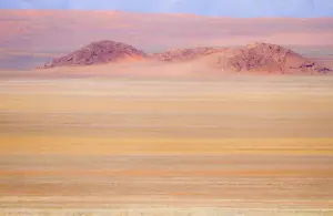 Africa, Namibia. Heat distorts grassy plain and red sand dunes