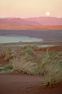 Africa, Namibia, Sossusvlei. The full moon rises over the NamibRand Nature Reserve in Sossusvlei