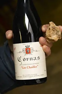 Holding Prints: Alberic Mazoyer showing in his hand a bottle of Cornas les Chailles and a stone