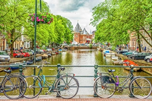 Bicycle Prints: Amsterdam, Netherlands. Wide angle landscape view of bicycles chained to a bridge overlooking a canal