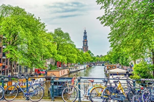 Bicycle Prints: Amsterdam, Netherlands. Wide angle view of Munttoren Tower at end of canal lined with boats and trees