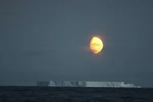 Antarctica, Gibbous moon rises above massive tabular iceberg in McFarlane Strait