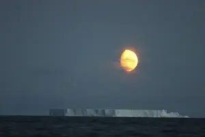 Cloudy Prints: Antarctica, Gibbous moon rises above massive tabular iceberg in McFarlane Strait
