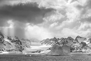 Antarctica, South Georgia Island. Sunbeams light up icebergs and mountains