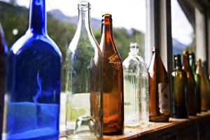 In A Row Prints: Antique glass bottles line the windowsill of a building, Gunns Camp, Hollyford Valley