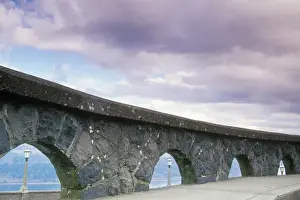 Brent Bergherm Prints: An arched stone rock wall frames three light posts overlooking the Columbia River
