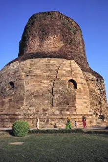 Uttar Pradesh Prints: Asia, India, Sarnath. Diminished figures walk in front of the pink-stoned Dhamekh Stupa