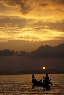Asia, Thailand, Phang Nga Bay. Father and boys rowing at sunset near Hat Khlang Muang