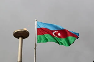 Azerbaijan, Baku. An Azerbaijan flag waves near a memorial flame