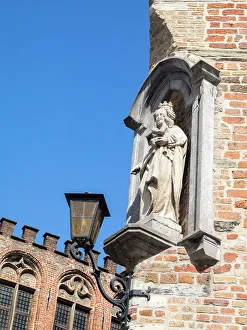 Brugge Prints: Belgium, Brugge. A stone statue on the cornerstone of a building