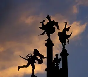 Ghent Prints: Belgium, Ghent. Silhouette of stone figures atop building, colored cloud background