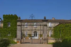Opening Prints: A black iron gate and main chateau building at Chateau Canon Saint Emilion Bordeaux