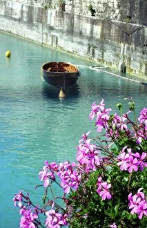 A boat drifts in a canal in Peschiera del Garda on the shores of Lake Garda, Italy