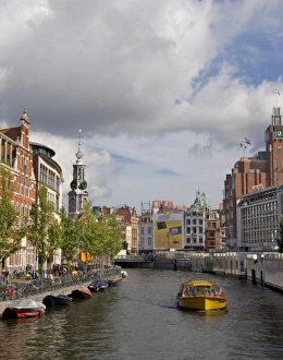 A boat travel down a canal near the flower market with the steple of Muntplein A boat travel down a canal near the flower market with the steple of Muntplein