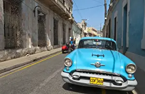 Images Dated 2029: Camaquey Cuba street scene of old Oldsmobile car on street and buildings