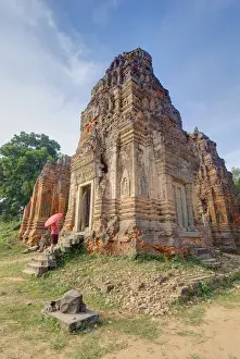 Cambodia, Angkor Wat. Female tourist with umbrella views part of Lolei Temple. Credit as