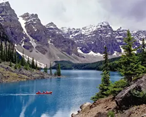 Canada, Alberta, Moraine Lake. A canoe glides across beautiful Moraine Lake in