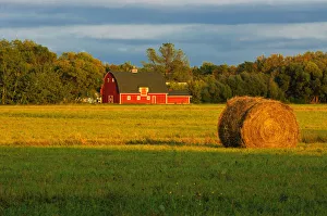 Hay Bale Prints: Canada, Manitoba, Matlock. Red barn and bale at sunrise
