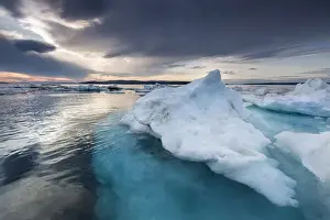 Canada, Nunavut, Territory, Afternoon sun lights storm clouds above melting iceberg