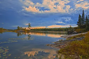 Images Dated 23rd March 2020: Canada, Ontario, Kenora District. Forest autumn colors reflect on Middle Lake at sunrise