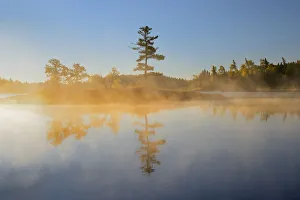 Canada, Ontario, Kenora. Sunrise reflections on Middle Lake fog