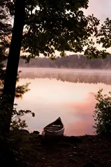 Images Dated 25th September 2008: A canoe rests on the shore of Pawtuckaway Lake at dawn as seen from Horse Island