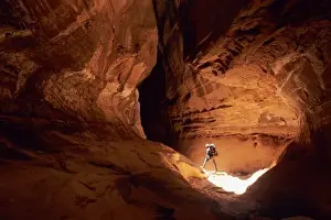 Search Prints: Canyoneer illuminated in the depths of a narrow canyon in the Dirty Devil Canyon