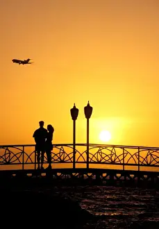 Oranjestad Prints: Caribbean, Aruba, Oranjestad. Couple enjoying sunset with plane overhead
