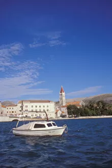 The Cathedral of Saint Lovro in Trogir stands behind a small boat in the Trogir Canal