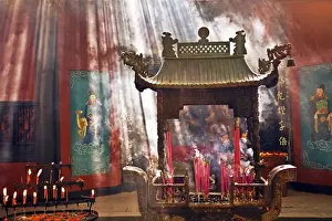 Deity Prints: China, Hangzhou, Lingyin Buddhist Temple candles and incense burn at an alter as buddists pray