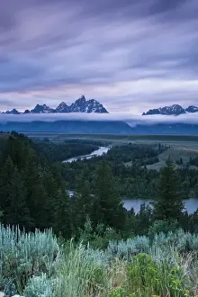 Winding Prints: Clouds illuminate with red light above the Grand Teton mountains seen from the Snake