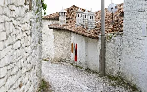 Images Dated 11th July 2006: Cobble stone street with traditional ottoman white stone houses. An Albanian flag on the wall