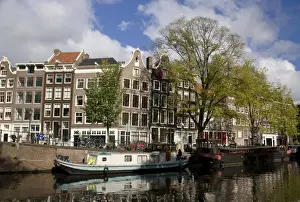 Marilyn Parver Prints: Colorfu buildings line an Amsterdam canal with a houseboat parked out front