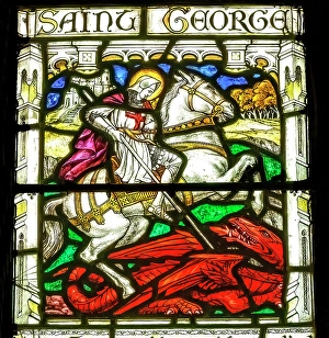 Prints of Colorful St. George and the Red Dragon stained glass, St. Petroc Church, Dartmouth, Devon, England. St. George allegedly killed dragon in 1000 AD. Church originally founded in 1192 Images Dated 2024 December: Colorful St. George and the Red Dragon stained glass