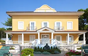 Pleasant Prints: Cres, Coatia - A two level, yellow house with a large porch and well manicured garden