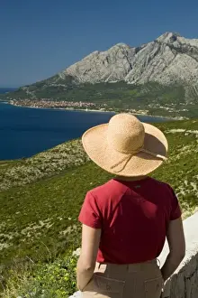 Peljesac Prints: Croatia, Dalmatia, Female tourist in straw hat gazes at lush fields and town of Orebic