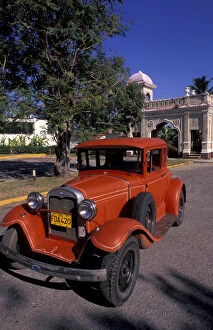Images Dated 5th October 2004: Cuba, Cien Fuergos, Old Model A Ford and colorful architecture behind