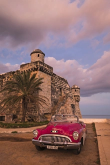 Spanish Speaking Prints: Cuba, Cojimar. Classic American car parked in front of a fort